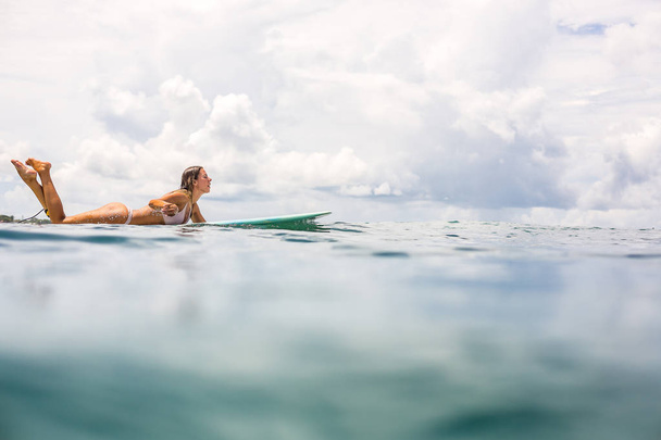 Beautiful young surfer woman in sexy pink bikini paddle surfing longboard on big waves in open ocean. Modern family lifestyle, people water sport adventure camp and extreme swim on summer vacation. - Foto, Imagem