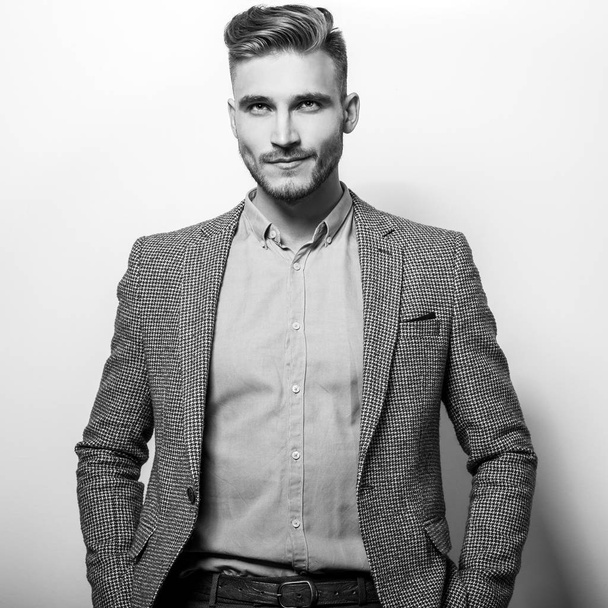Handsome young elegant man in grey jacket pose against studio background.  - 写真・画像