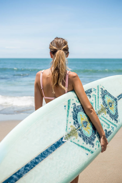Beautiful young slim girl in sexy pink bikini with long custom surfing board single fin in front of blue ocean ready to surfing. Tropic island vacation. Summer travel girl, active hipster lifestyle. - Zdjęcie, obraz
