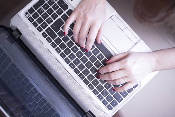 Секретарша печатает на ноутбуке клавиатуры компьютера клавиши с руками с красным лаком для ногтей
. - Фото, изображение