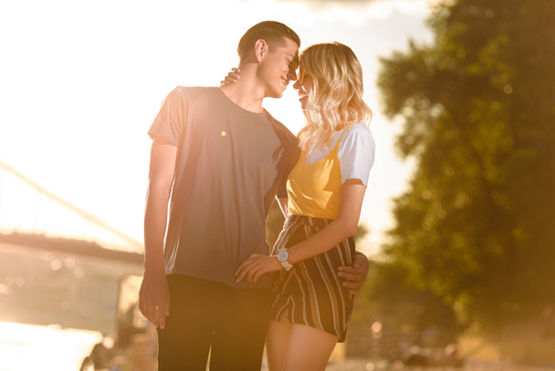 молодая пара обнимается и собирается целоваться на берегу реки во время заката
 - Фото, изображение