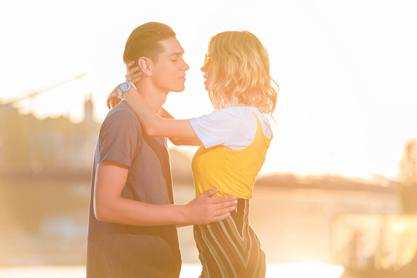 vista lateral do jovem casal que vai beijar na praia do rio à noite
 - Foto, Imagem