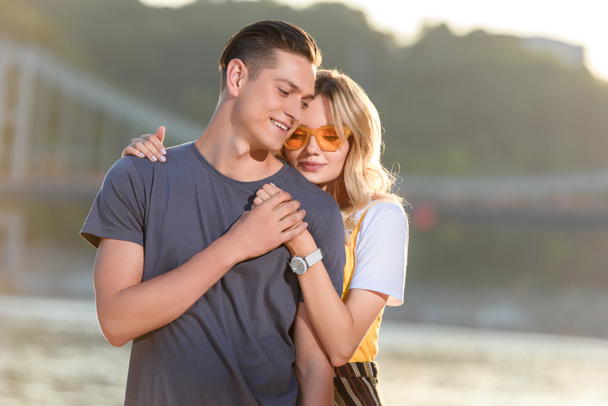 girlfriend hugging boyfriend on river beach in evening - Фото, зображення