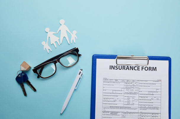 vue du haut du formulaire d'assurance, lunettes, stylo, famille de coupe de papier et clés isolées sur bleu
     - Photo, image