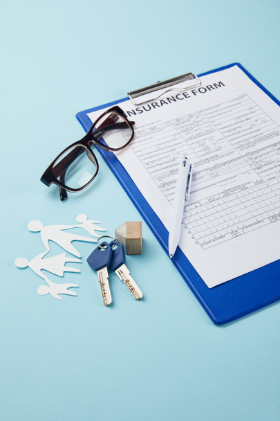 vue rapprochée du formulaire d'assurance, du stylo, de la famille du papier découpé et des clés isolées sur bleu
    - Photo, image