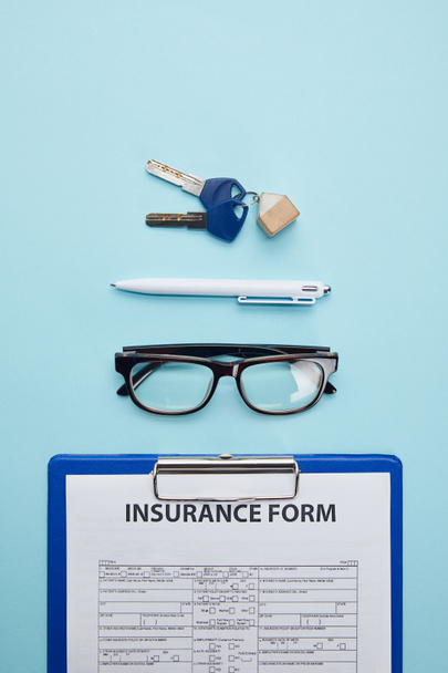 top view of insurance form, eyeglasses, pen and keys isolated on blue  - Foto, imagen