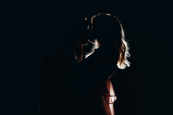 silhuetas de casal apaixonado beijando no escuro
 - Foto, Imagem