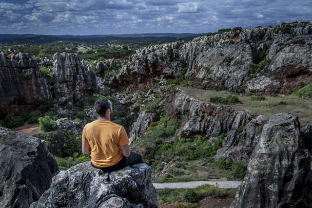 Vista laterale dell'uomo irriconoscibile seduto sulla scogliera e che distoglie lo sguardo mentre si rilassa nella natura a Cerro del Hierro, Siviglia
 - Foto, immagini