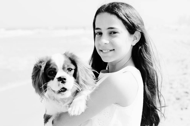 Portrait of  12 years old girl walking with her dog on the beach in summer day - Photo, Image