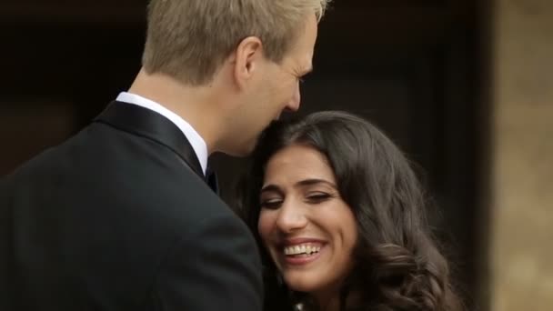 Romantic portrait of the beautiful cheerful couple of newlyweds tenderly kissing outdoor. - Záběry, video