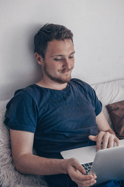 Kirjoitan uutta blogiviestiä. Tekniikka, koti - elämäntapa konsepti lähikuva miehestä, joka työskentelee kannettavan tietokoneen kanssa ja istuu sängyssä kotona
 - Valokuva, kuva