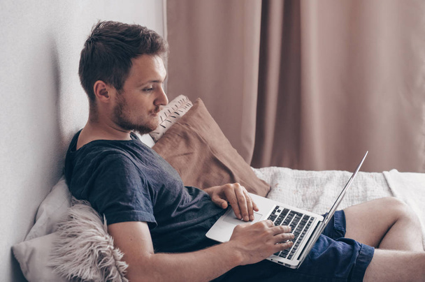 Typen nieuw blogbericht. Technologie, home - lifestyle concept close up van man werken met laptopcomputer en zittend op bed thuis - Foto, afbeelding