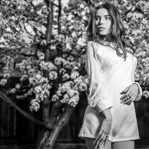 Portrait of beautiful young woman in autumn garden against blooming cherry. Black-white photo. - Foto, immagini