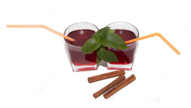Sirup aus roten Johannisbeeren in Gläsern auf weißem Hintergrund und Zimtstangen. ein süßes Getränk. Trinken aus Beeren - Foto, Bild
