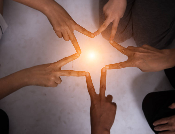 Crear dedo es la forma de la estrella del trabajo en equipo. equipo de manos unidas, el proyecto de colaboración, tono de luz cálido en el centro de la estrella, luz borrosa alrededor
. - Foto, Imagen