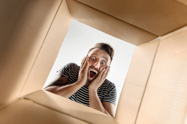 Man unpacking and opening carton box and looking inside - Fotografie, Obrázek