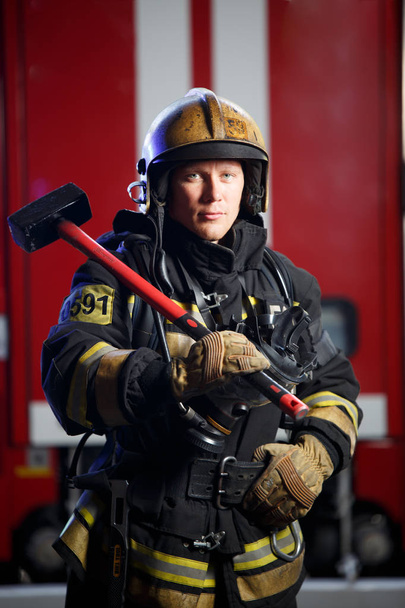 Photo of fireman with sledgehammer in hands near fire engine - Foto, Imagem