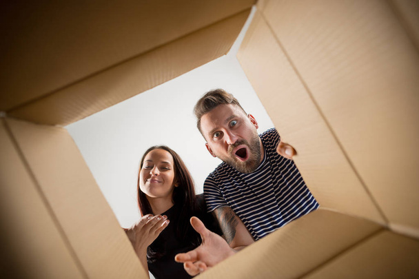 The couple unpacking and opening carton box and looking inside - Foto, Bild