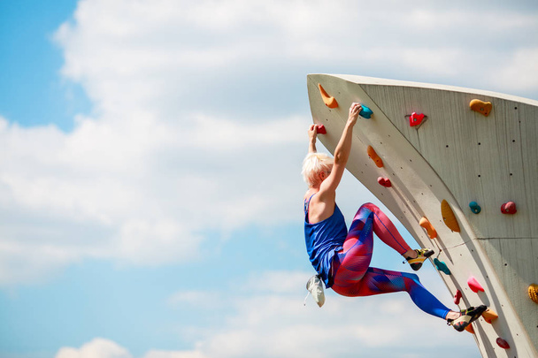 Image from side of sports woman climbing on rocky summer day - Valokuva, kuva