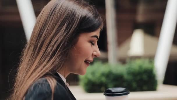 Professional young businesswoman walking on urban street using smartphone and drink coffee. Concept: new business, communication, banker. Outside, slow motion - Materiał filmowy, wideo