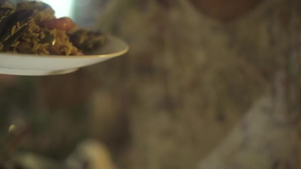 伝統的なパエリア料理スペイン料理のレストランで準備の手を持つ男。板で新鮮な魚介類と野菜のスペインのパエリアを抱きかかえた. - 映像、動画