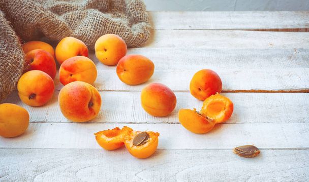 ripe apricots on wooden table, rough burlap sack, close-up, selective focus - Foto, immagini