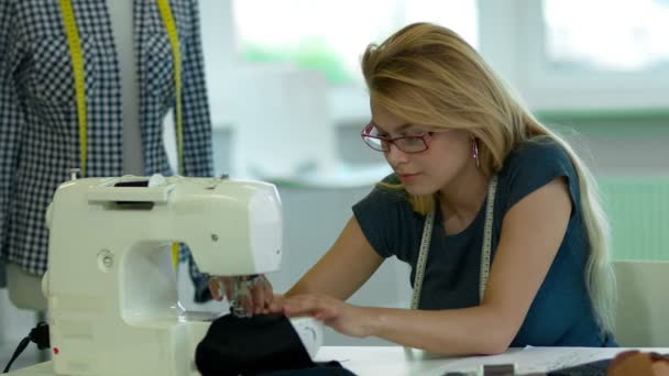 Chica está cosiendo un paño en una máquina de coser
. - Imágenes, Vídeo