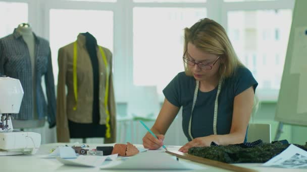 Κορίτσι σχεδιαστής σύρει ένα σκίτσο του ένα κοστούμι από μολύβι, στη συνέχεια, μιλώντας από τηλεφώνου. - Πλάνα, βίντεο