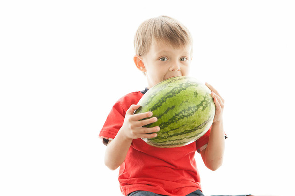 A cute boy and a big green watermelon. The child smiles and rejoices. - Fotoğraf, Görsel