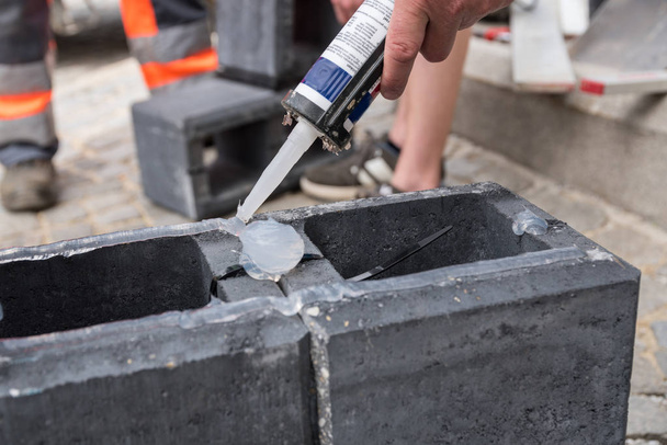 Maçons trabalham na indústria da construção com um tubo de silicone e telhas de concreto - close-up
 - Foto, Imagem