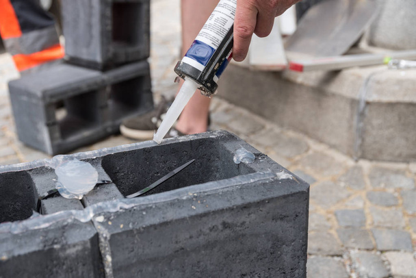 Metselaar op een bouwplaats met betonnen tegel en siliconen - close-up - Foto, afbeelding