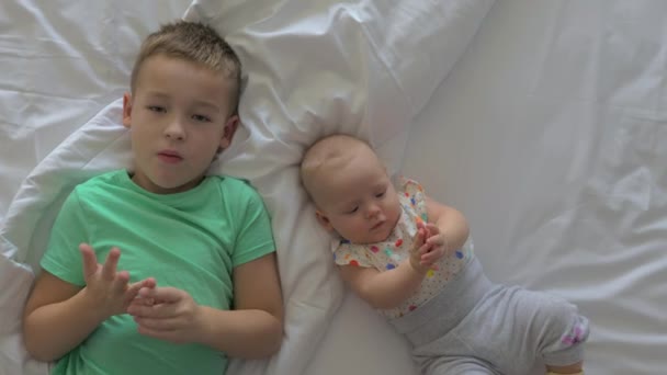 Jongen en baby meisje broers en zussen op bed thuis - Video