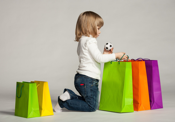 Little girl sitting near shopping bags - Фото, зображення