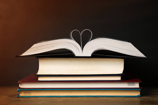 Könyv oldal szív alakú sötét háttérrel. Fogalmi szív könyvből. Másolja a hely - Fotó, kép