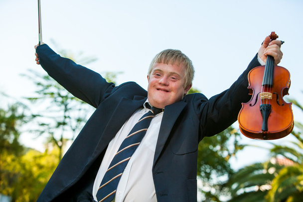 Friendly handicapped boy raising violin outdoors. - Photo, Image