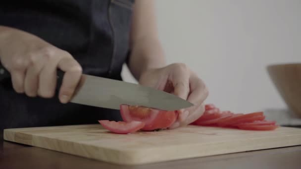Close up of chief woman making salad healthy food and chopping tomato on cutting board in the kitchen. - Filmati, video