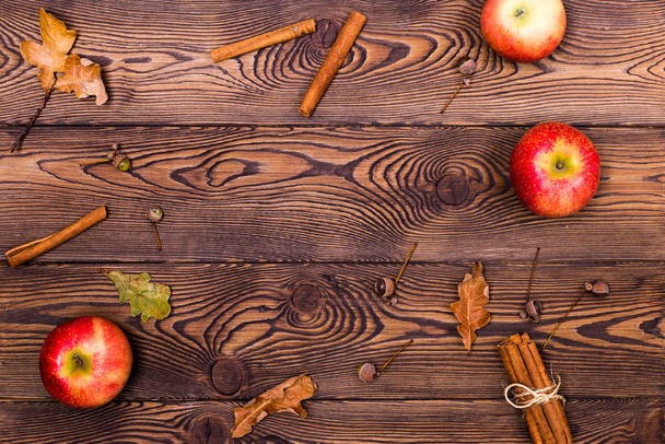 Fondo de madera con manzanas, canela y hojas amarillas caídas de roble y bellota. Puesta plana
 - Foto, Imagen