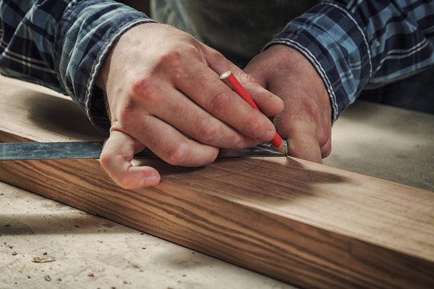 Detailní záběr Muž měří dřevěnou desku s pravítkem a tužkou označí potřebné body pro řezy - Fotografie, Obrázek