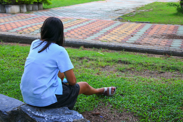 γυναίκα που κάθεται στο γρασίδι σε ένα δημόσιο πάρκο - Φωτογραφία, εικόνα