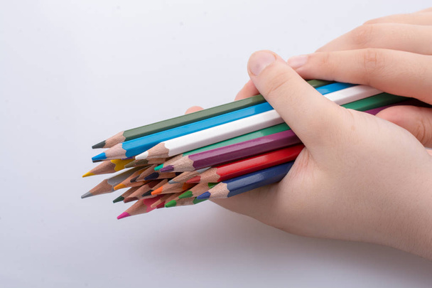 Hand holding color Pencils placed on a white background - Фото, зображення