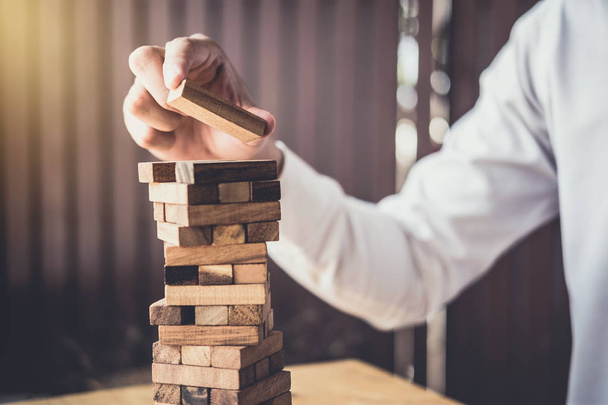 Images of hand of businesspeople placing and pulling wood block on the tower, Alternative risk concept, plan and strategy in business, Risk To Make Business Growth Concept With Wooden Blocks. - Фото, зображення