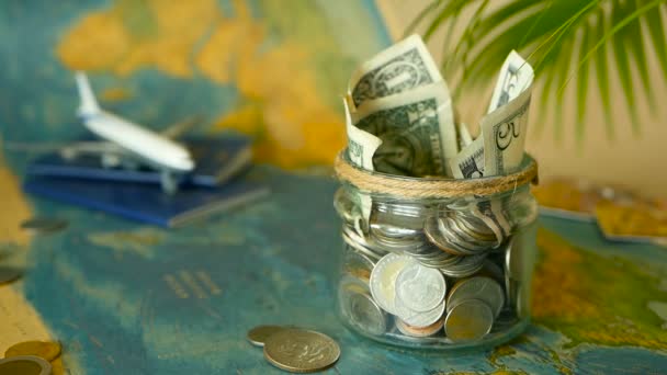 Reisekostenkonzept. Geld für Urlaub im Glas auf Weltkarte Hintergrund gespart - Filmmaterial, Video