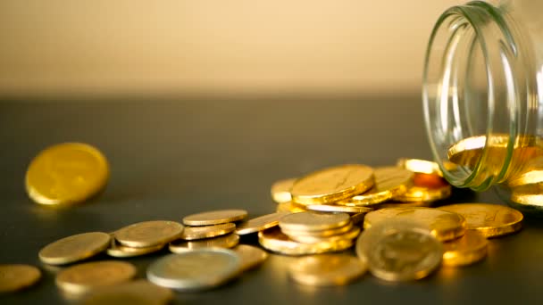 Nahaufnahme-Stillleben mit Goldmünzen auf schwarzem Tisch und rotierendem Groschen. Gelbe Münzen fielen aus Glas. - Filmmaterial, Video