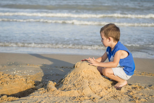 süßer kleiner Junge spielt mit Sand am tropischen Strand - Foto, Bild