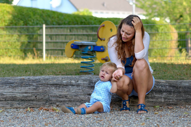 Troubled stressato giovane madre con il suo pianto infelice bambino all'aperto in un parco giochi
 - Foto, immagini
