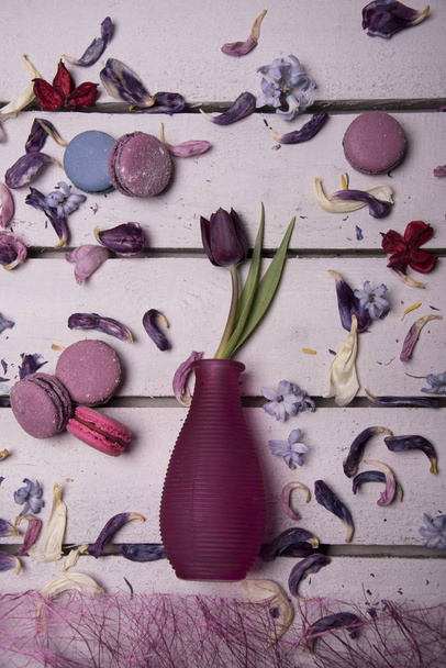 tulipán púrpura en jarrón con macarrones de colores sobre fondo de madera
 - Foto, imagen