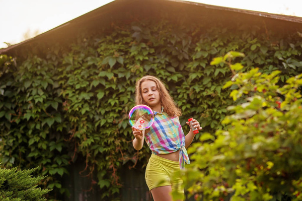 Kabarcıklar yaz bahçede günbatımında üfleme kız çocuk. - Fotoğraf, Görsel