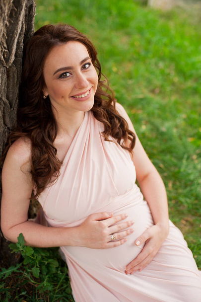 Glimlachend zwangere vrouw 25-29 jaar oude rusten door het meer. Poseren buitenshuis. Moederschap. Moederschap. - Foto, afbeelding