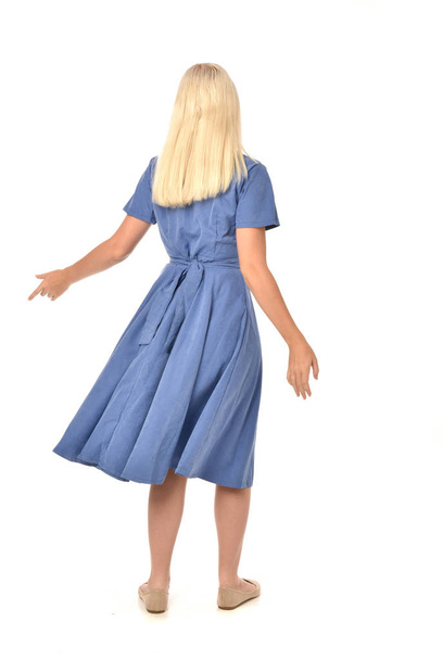 full length portrait of blonde girl wearing blue dress. standing pose with back to the camera. isolated on white  studio background. - 写真・画像