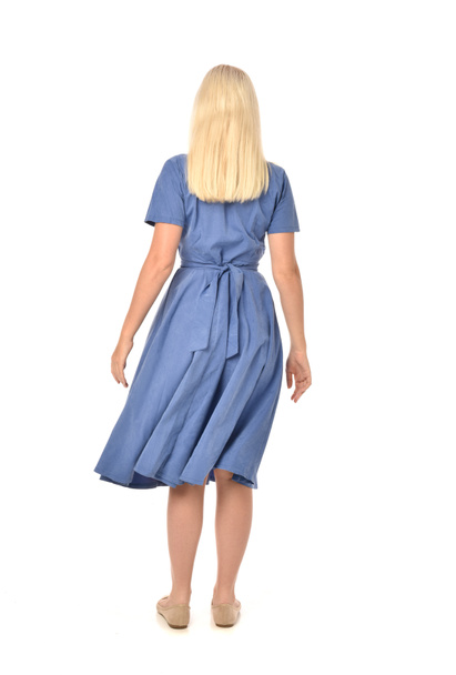Portret van de volledige lengte van blond meisje draagt blauwe jurk. staande poseren met de rug naar de camera. geïsoleerd op witte studio achtergrond. - Foto, afbeelding